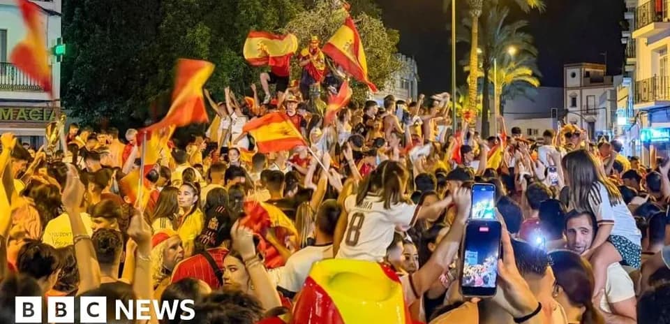 Celebration crowd waving Spanish flags at night