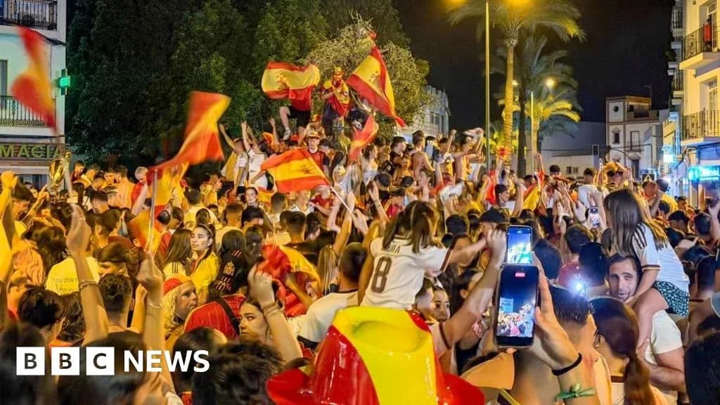 Celebration crowd waving Spanish flags at night