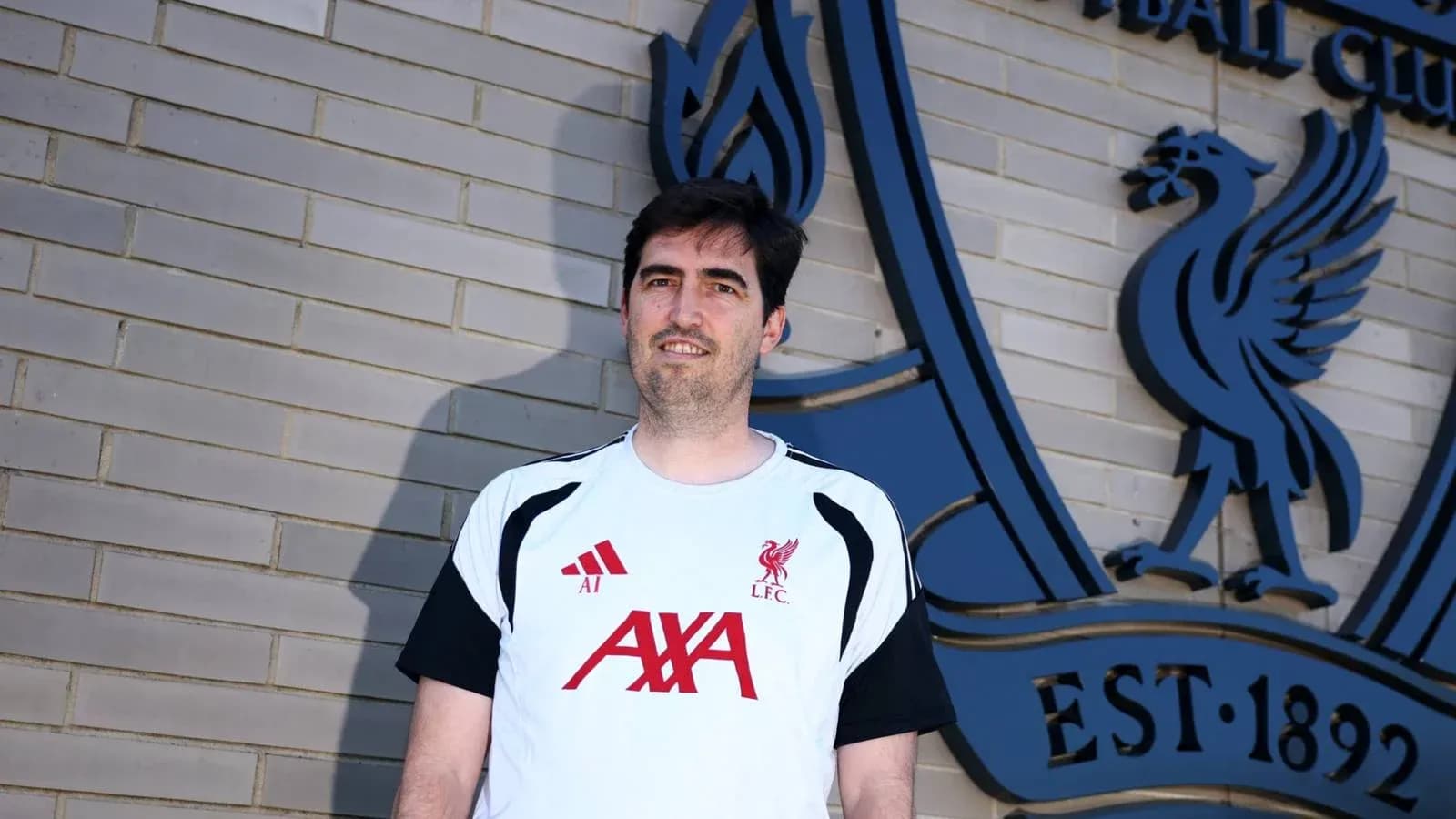 Persona de pie frente al escudo del Liverpool FC