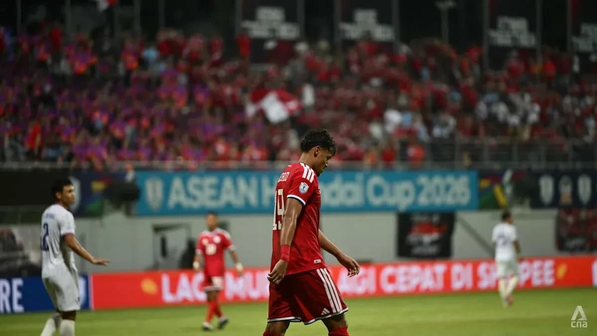 Jugador con camiseta roja caminando cabizbajo en el campo