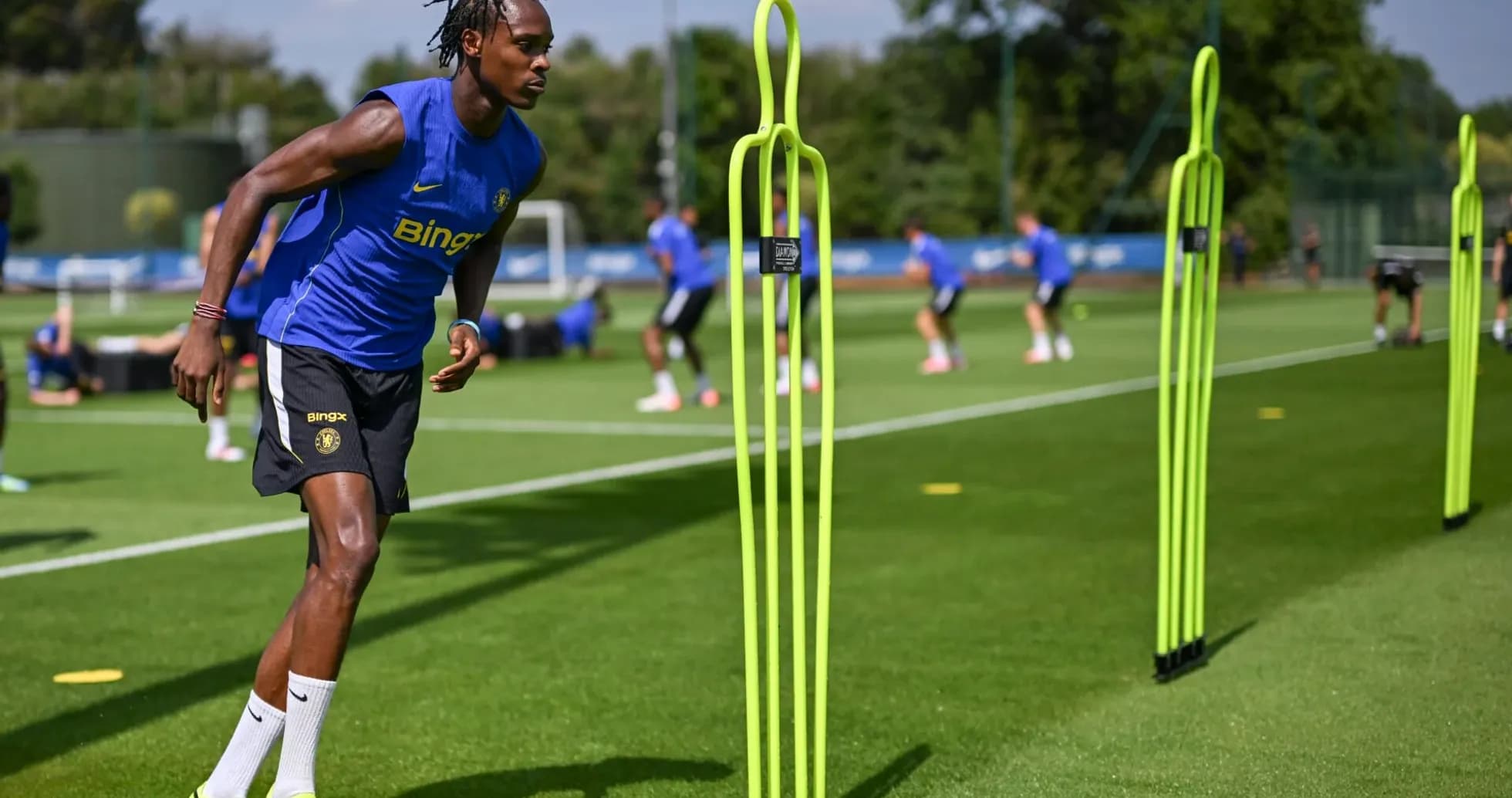 Jugador entrenando con conos en campo de fútbol