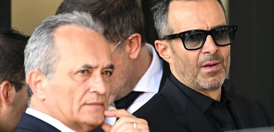 Dos hombres en trajes oscuros conversando afuera