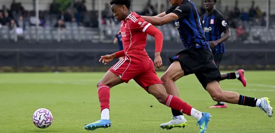 Jugador en camiseta roja driblando mientras es perseguido