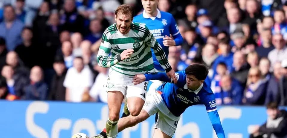 Jugador de Celtic superando a rival de Rangers en el suelo