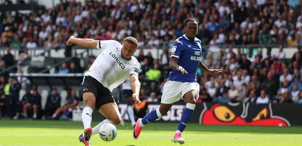 Jugador de Derby intentando despejar el balón ante rival