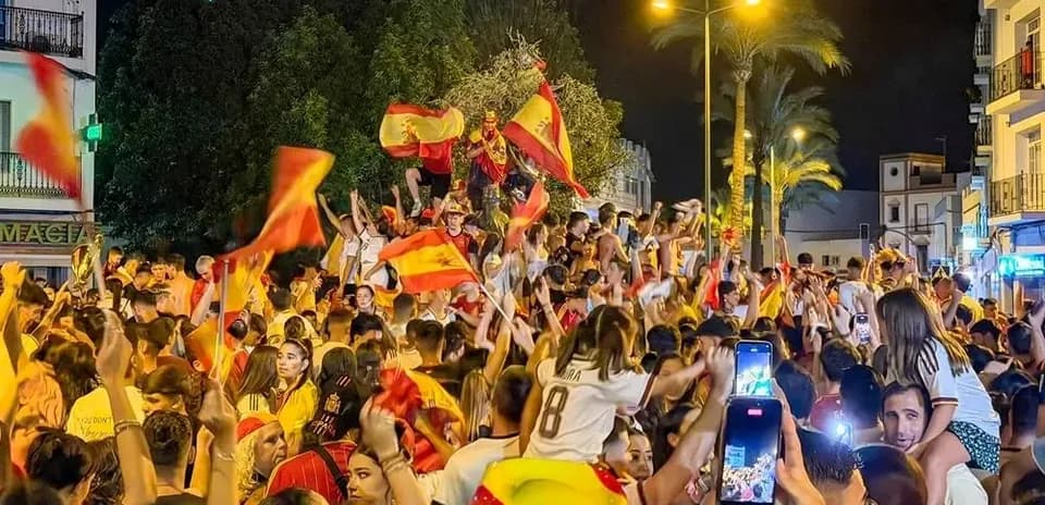 Celebration with fans waving Spanish flags at night