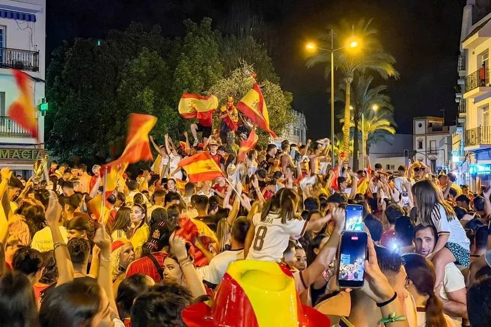 Celebration with fans waving Spanish flags at night