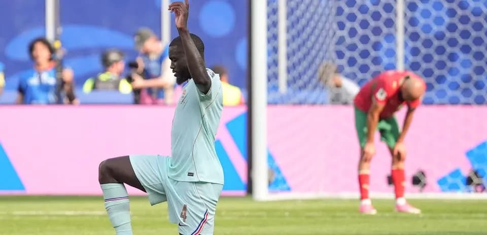 Jugador de fútbol celebrando mientras oponente se agacha