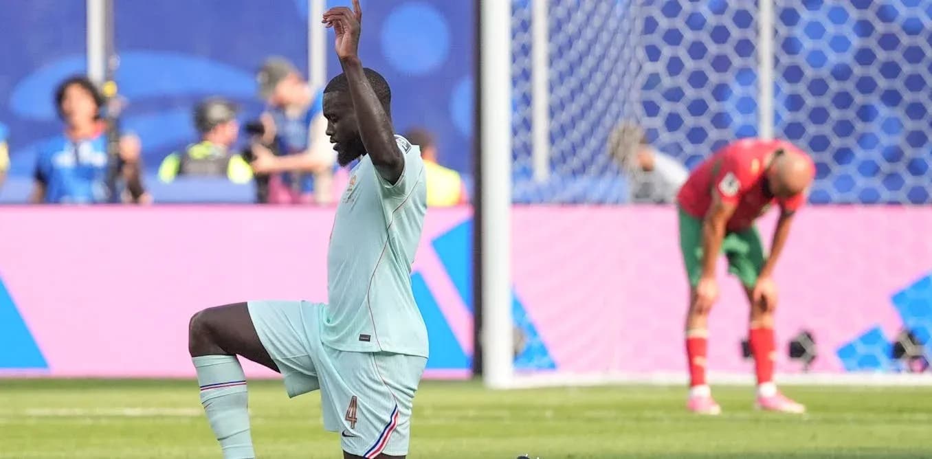 Jugador de fútbol celebrando mientras oponente se agacha