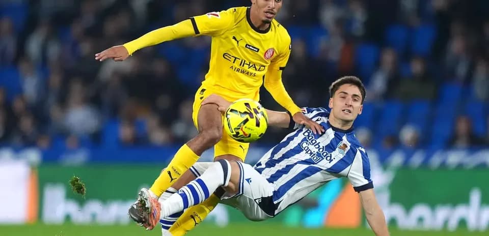 Jugador de Girona compitiendo contra jugador de Real Sociedad