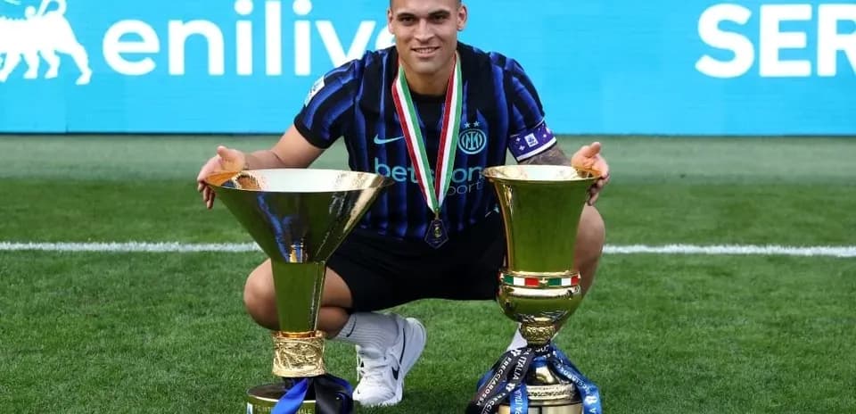 Jugador con dos trofeos en el campo de fútbol