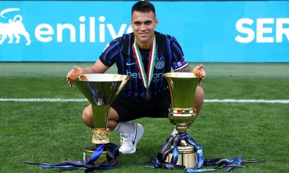 Jugador con dos trofeos en el campo de fútbol