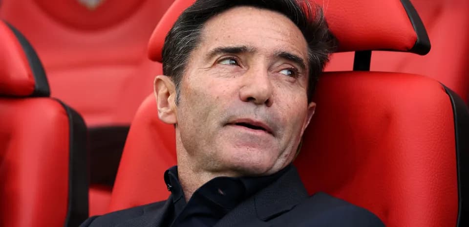 Entrenador sentado en banca con fondo rojo