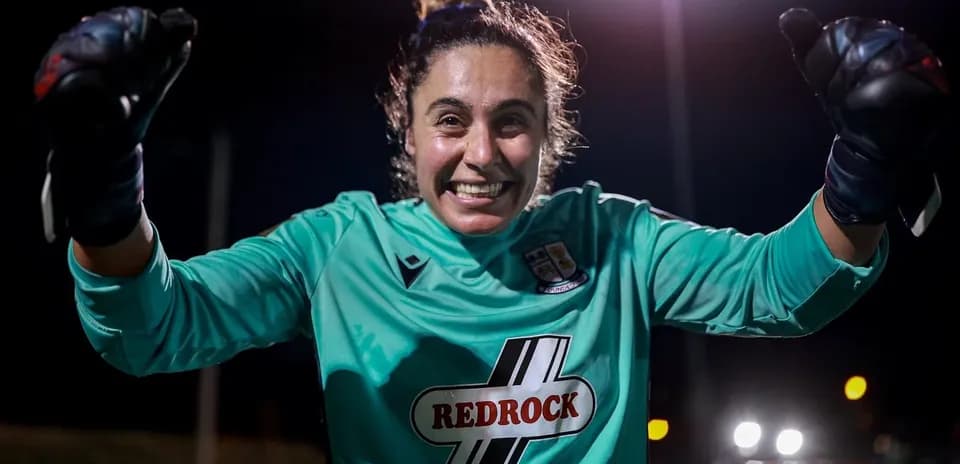 Portera sonriente con guantes levantando los puños