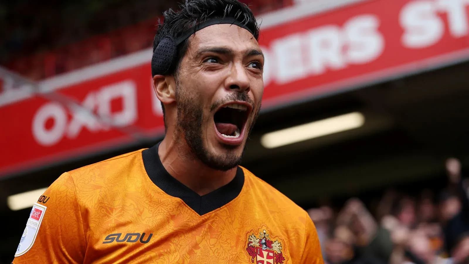 Jugador celebrando con camiseta naranja en estadio