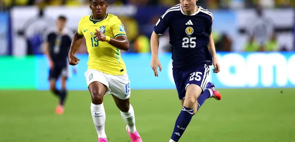 Jugador de Escocia corriendo con el balón, seguido por brasileño