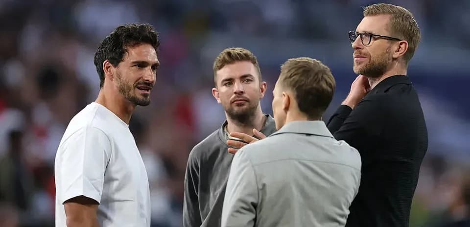 Cuatro hombres conversando en el campo de fútbol