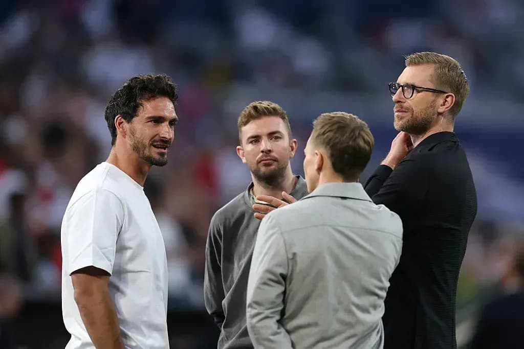 Cuatro hombres conversando en el campo de fútbol