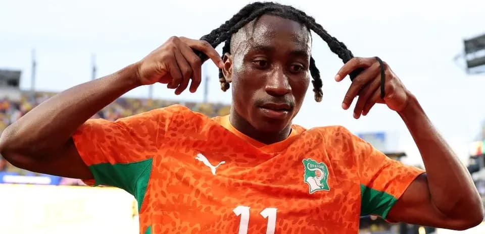 Jugador de fútbol ajustando su cabello en uniforme