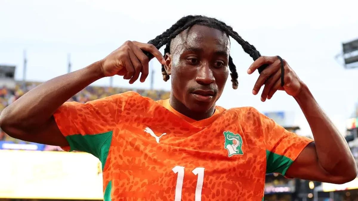Jugador de fútbol ajustando su cabello en uniforme