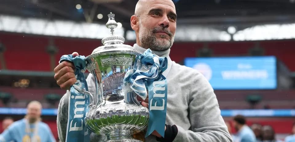 Entrenador sosteniendo trofeo en el estadio Wembley