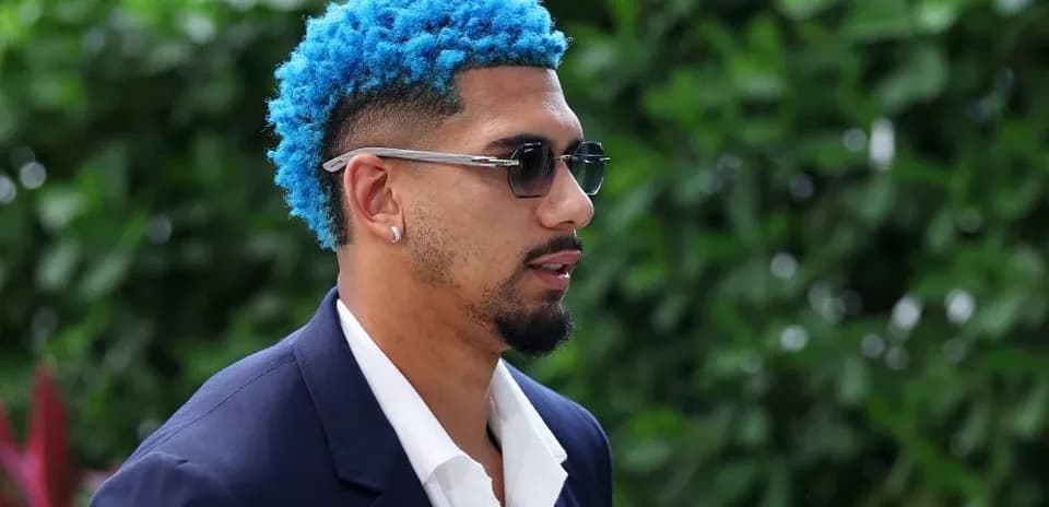 Jugador con cabello azul y traje oscuro caminando
