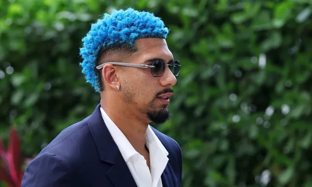 Jugador con cabello azul y traje oscuro caminando