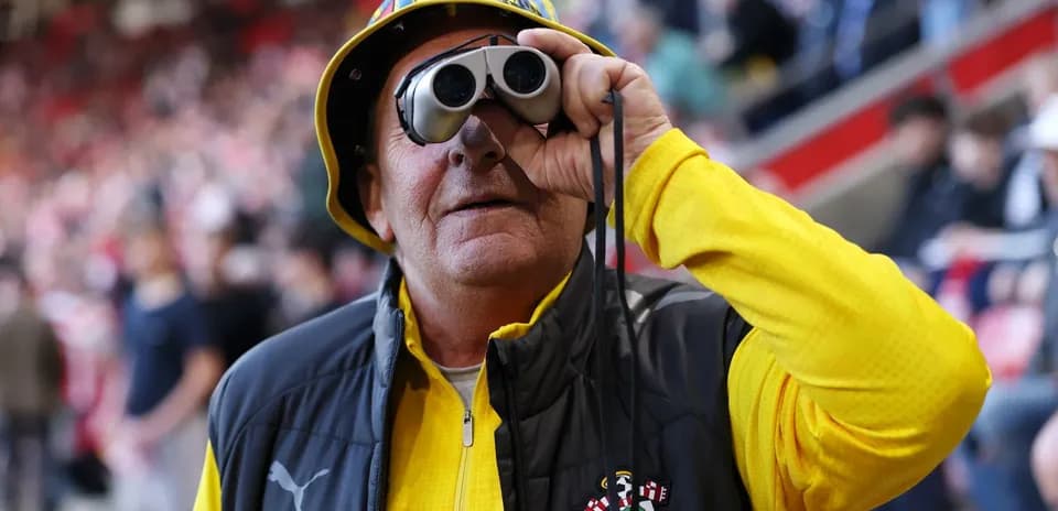 A fan wearing binoculars at a football match