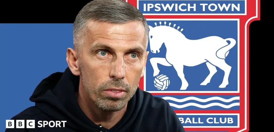 Entrenador hablando frente al escudo de Ipswich Town