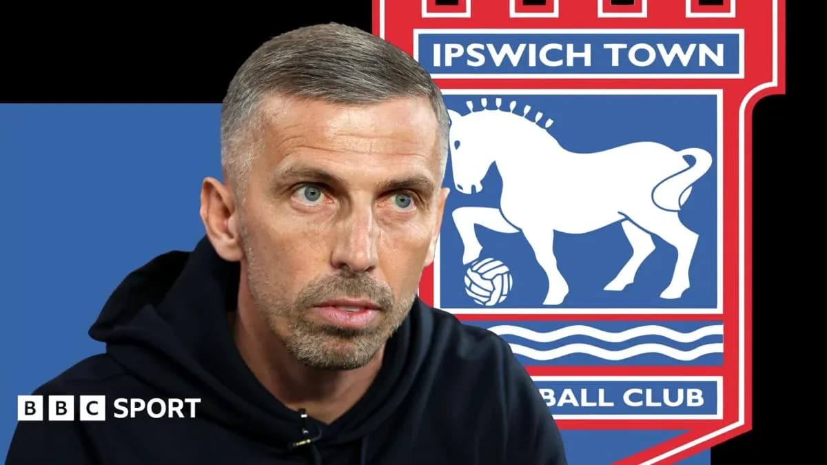 Entrenador hablando frente al escudo de Ipswich Town