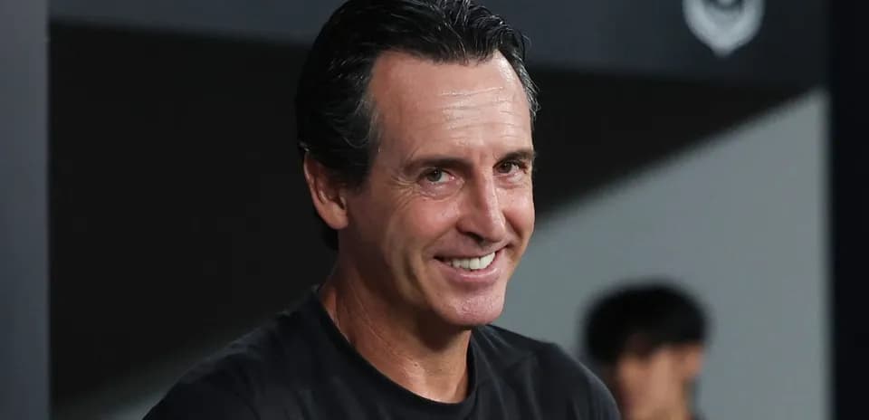 Entrenador sonriendo en el banquillo del estadio