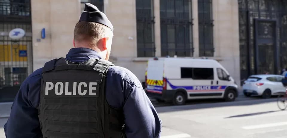 Policía de espaldas frente a furgón policial