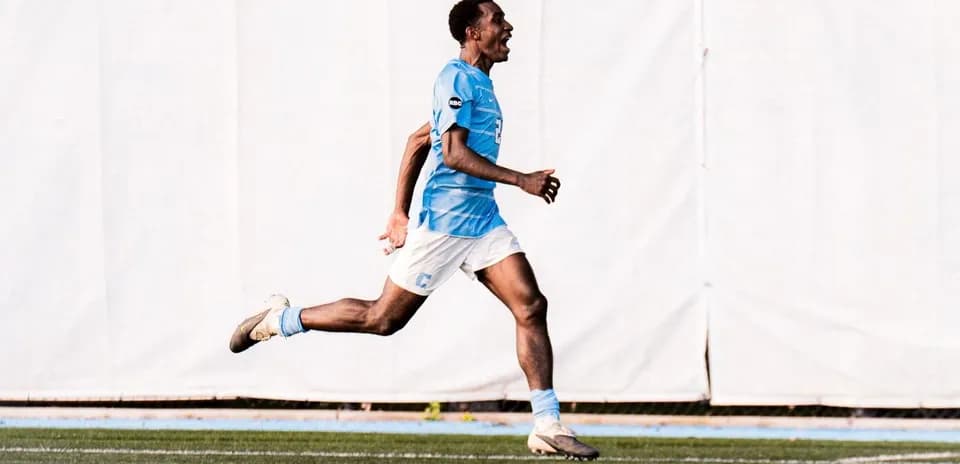 Jugador corriendo en campo con camiseta celeste