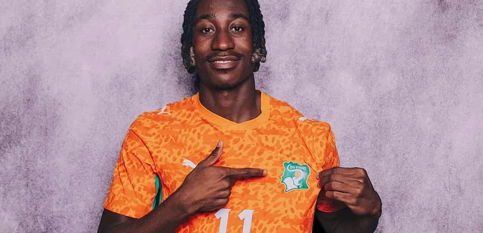 Jugador con camiseta de Costa de Marfil señalando escudo
