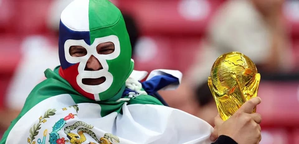 Fan in mask holding World Cup trophy