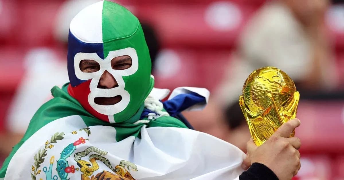 Fan in mask holding World Cup trophy