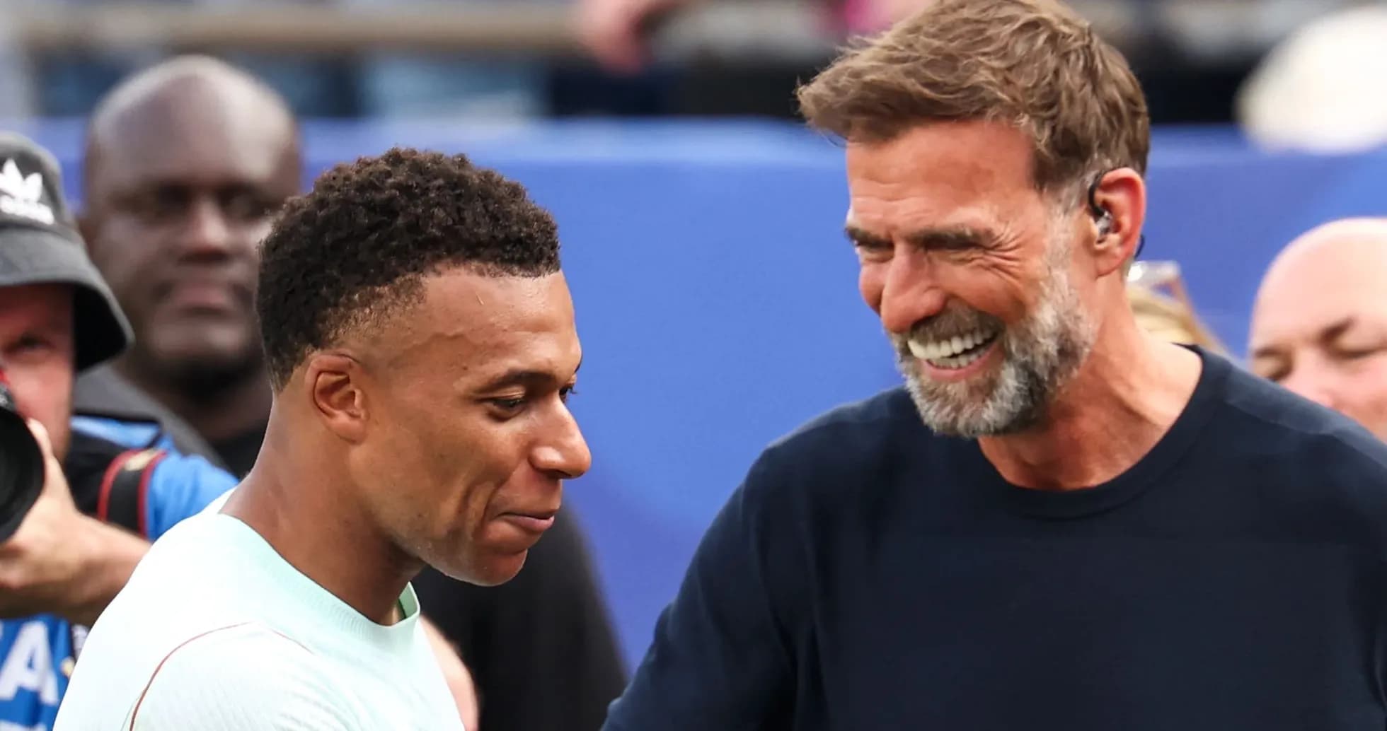 Kylian Mbappé y entrenador sonriendo durante encuentro