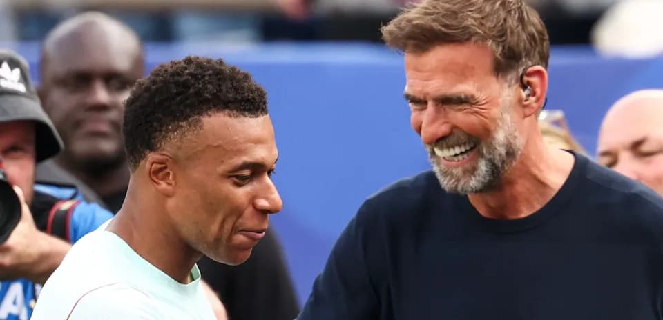 Kylian Mbappé y entrenador sonriendo durante encuentro
