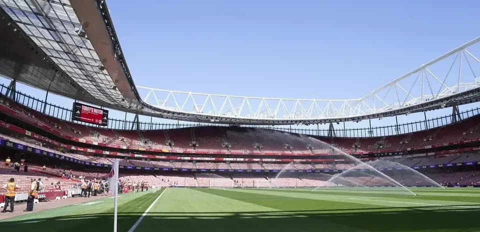 Estadio vacío con césped regado antes del partido
