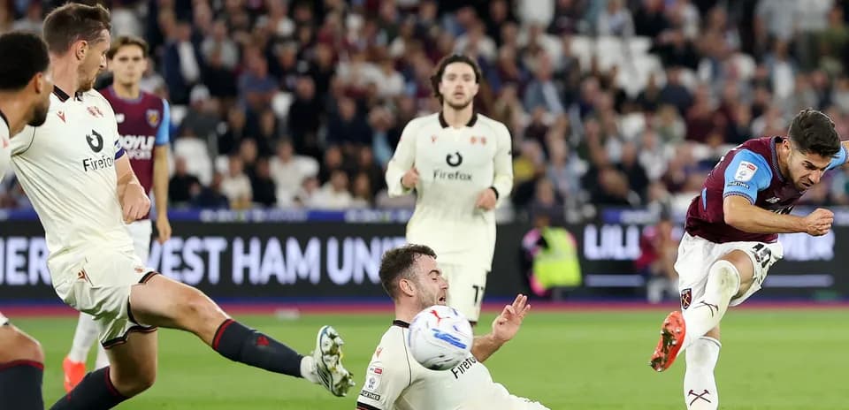 Jugador de West Ham disparando mientras rival cae al suelo
