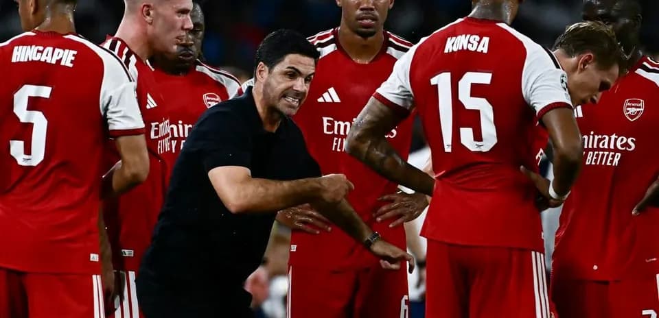 Entrenador instruyendo a jugadores de Arsenal durante reunión