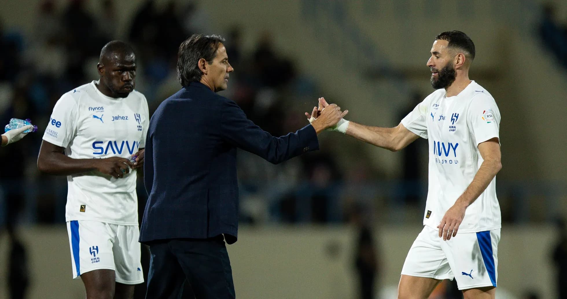 Entrenador saludando a jugador durante partido de fútbol