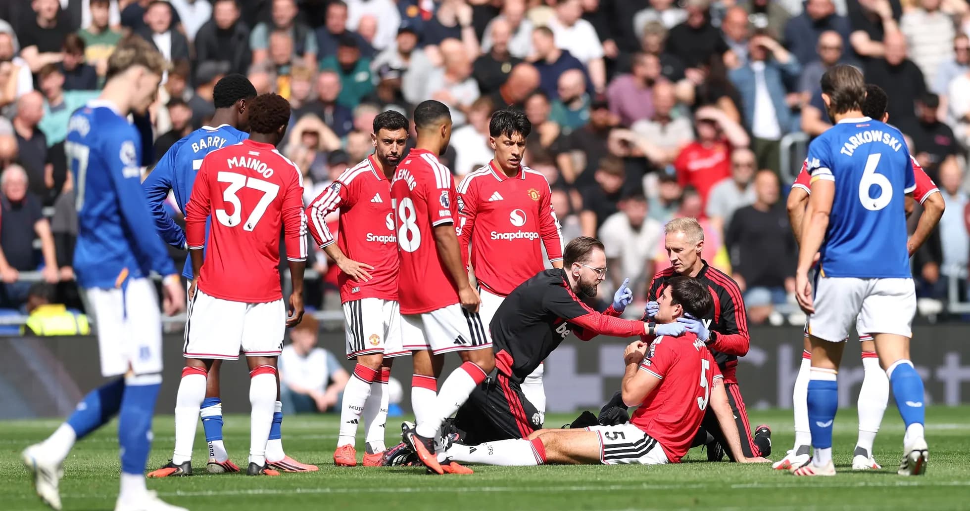 Jugadores de Manchester United rodeando a un compañero lesionado
