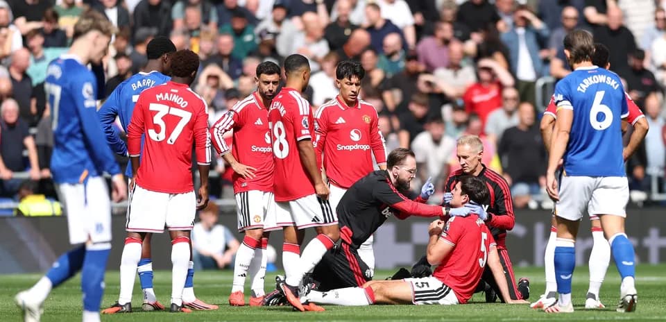 Jugadores de Manchester United rodeando a un compañero lesionado