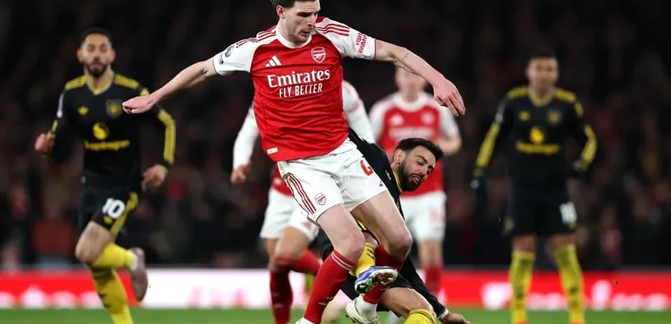 Jugador de Arsenal superando a rival en el suelo