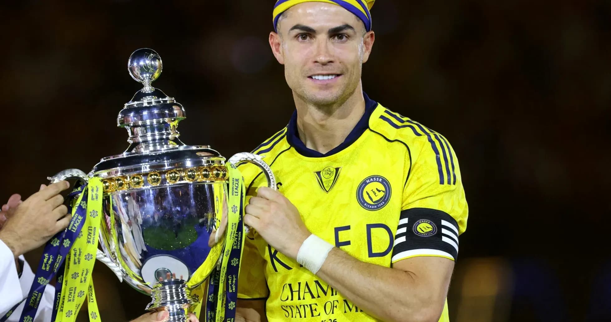 Jugador levantando trofeo con camiseta amarilla