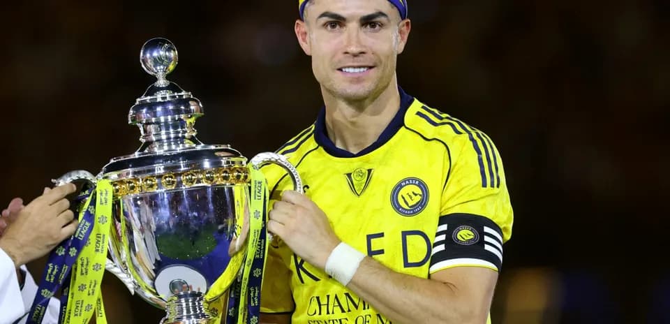 Jugador levantando trofeo con camiseta amarilla