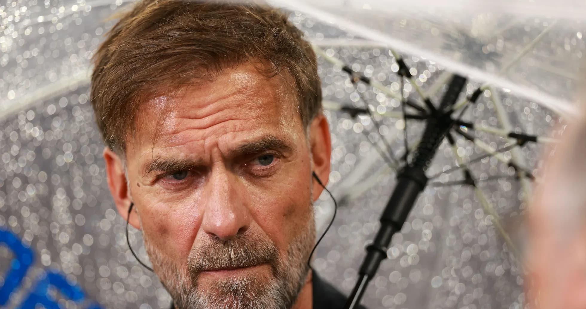 Entrenador bajo un paraguas en condiciones lluviosas