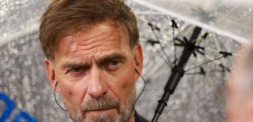 Entrenador bajo un paraguas en condiciones lluviosas