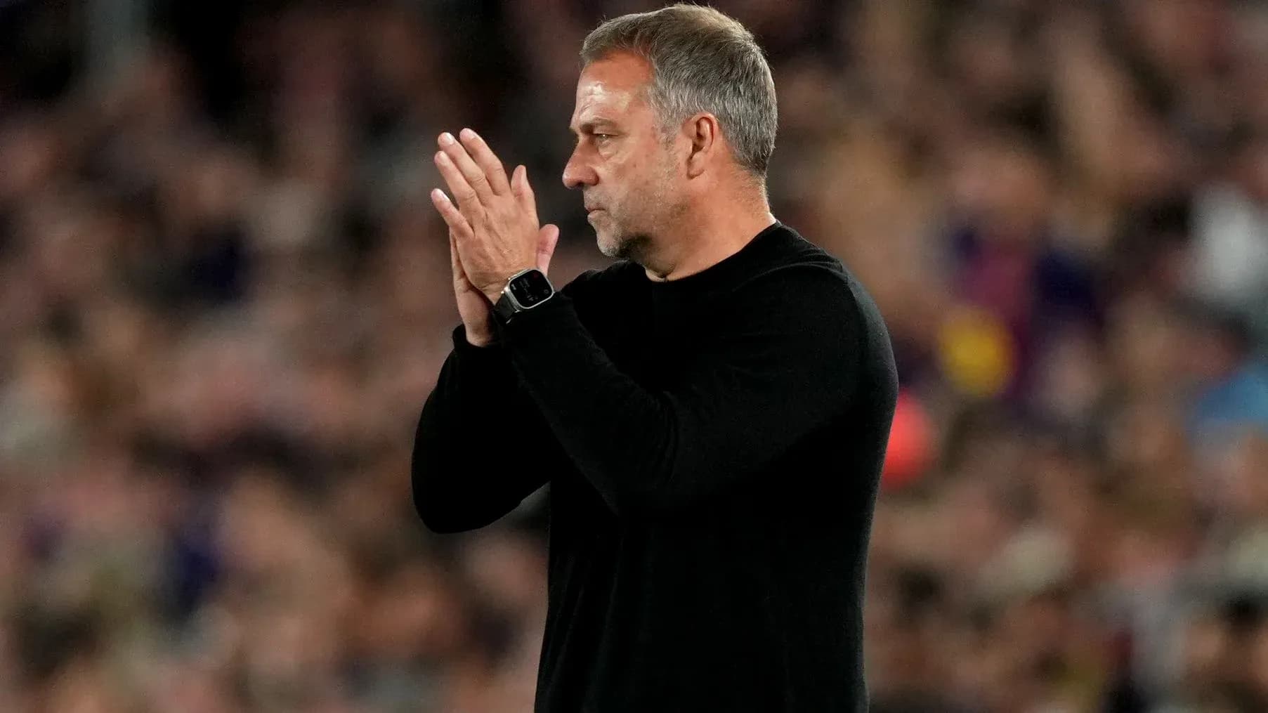 Entrenador aplaudiendo en el banquillo durante el partido